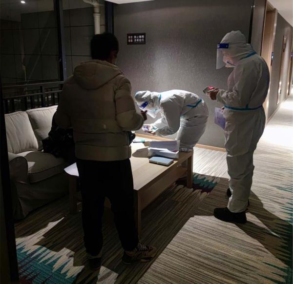 工作人员在酒店对中高风险地区司乘人员再次测温,查看48小时核酸证明