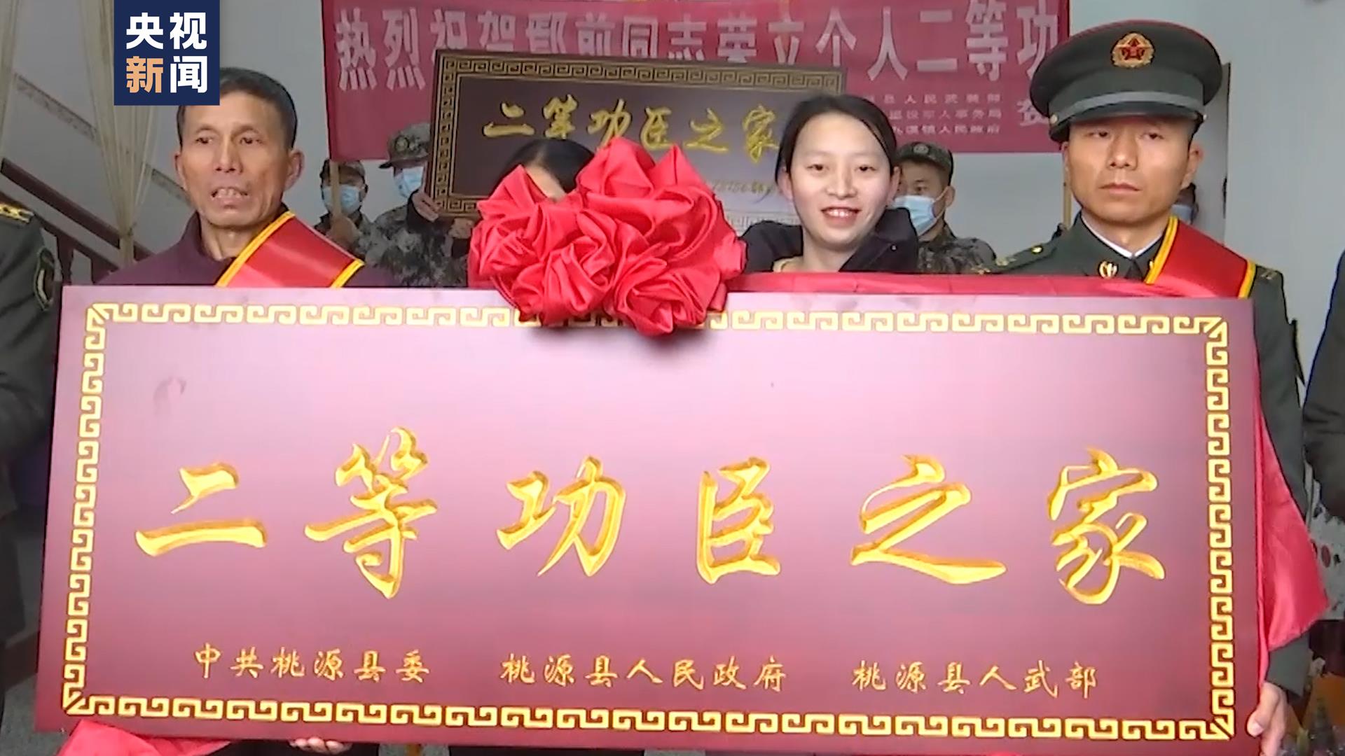 事迹,为鄢前及其家属佩戴绶带和红花,送上"二等功臣之家"牌匾并发放奖