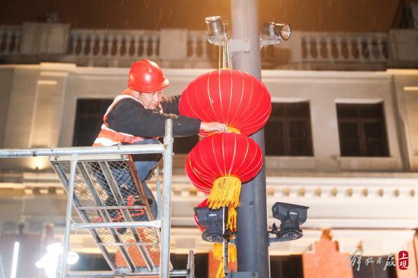 站在路灯脚手架上的工作人员彭常东,正在检查路灯灯笼的固定情况.