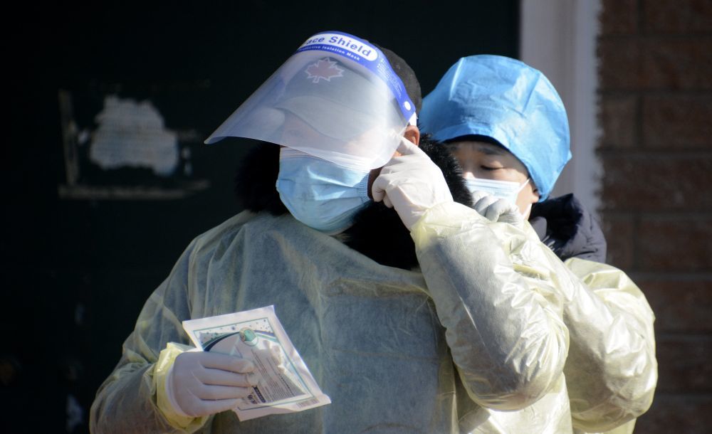 ↑1月25日，丰台区东高地街道的志愿者在核酸检测现场穿防护服。