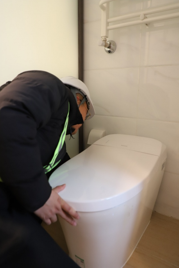 「梁佳男正在检查马桶缝隙是否有灰尘」