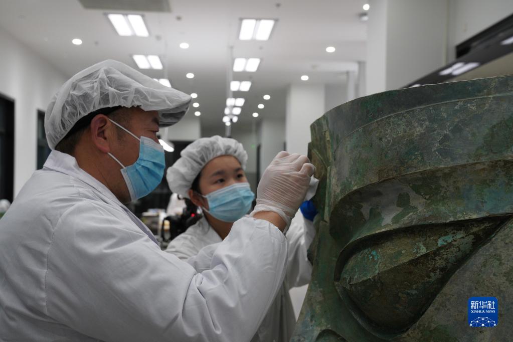 文保人员正在对三星堆遗址出土的青铜大面具进行修复（资料图片）。新华社发（四川省文物考古研究院、三星堆博物馆供图）