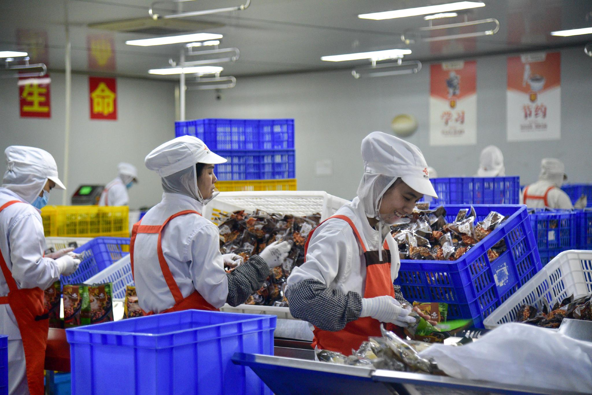 △ 广西柳州，工人在螺蛳粉生产车间生产线上包装袋装螺蛳粉。