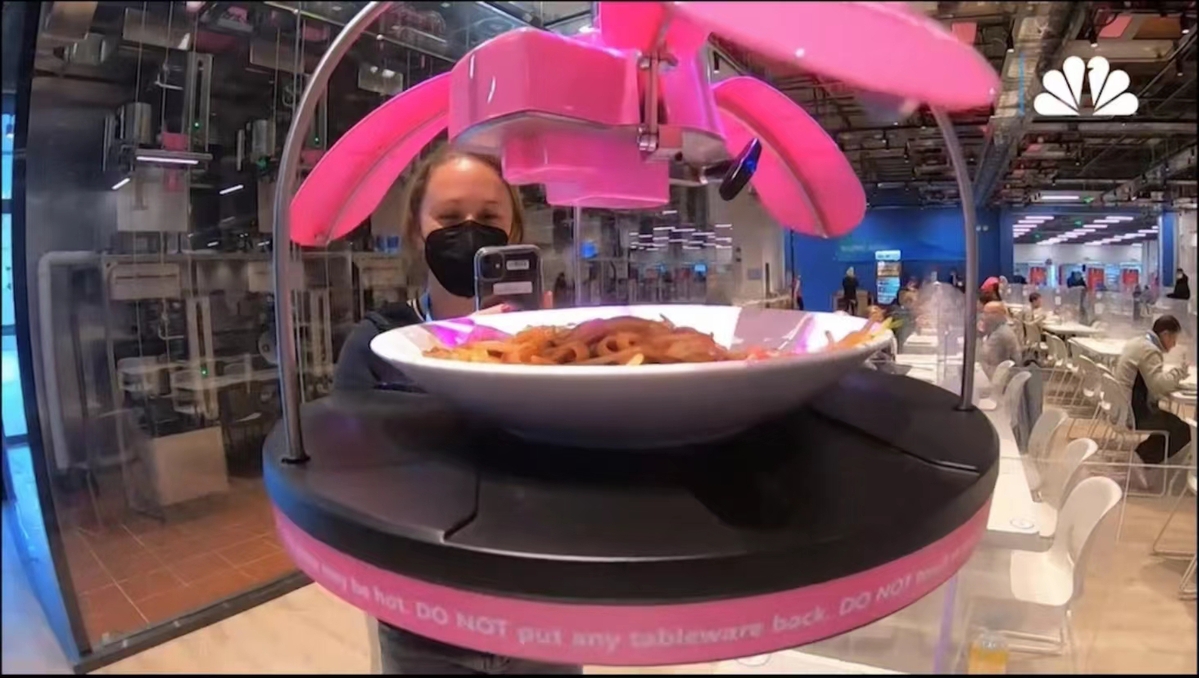 为了尽量减少人与人之间的接触，餐厅中的“机器人大厨”给各国运动员和代表带来了新的用餐体验。（图片来源：视频截图）