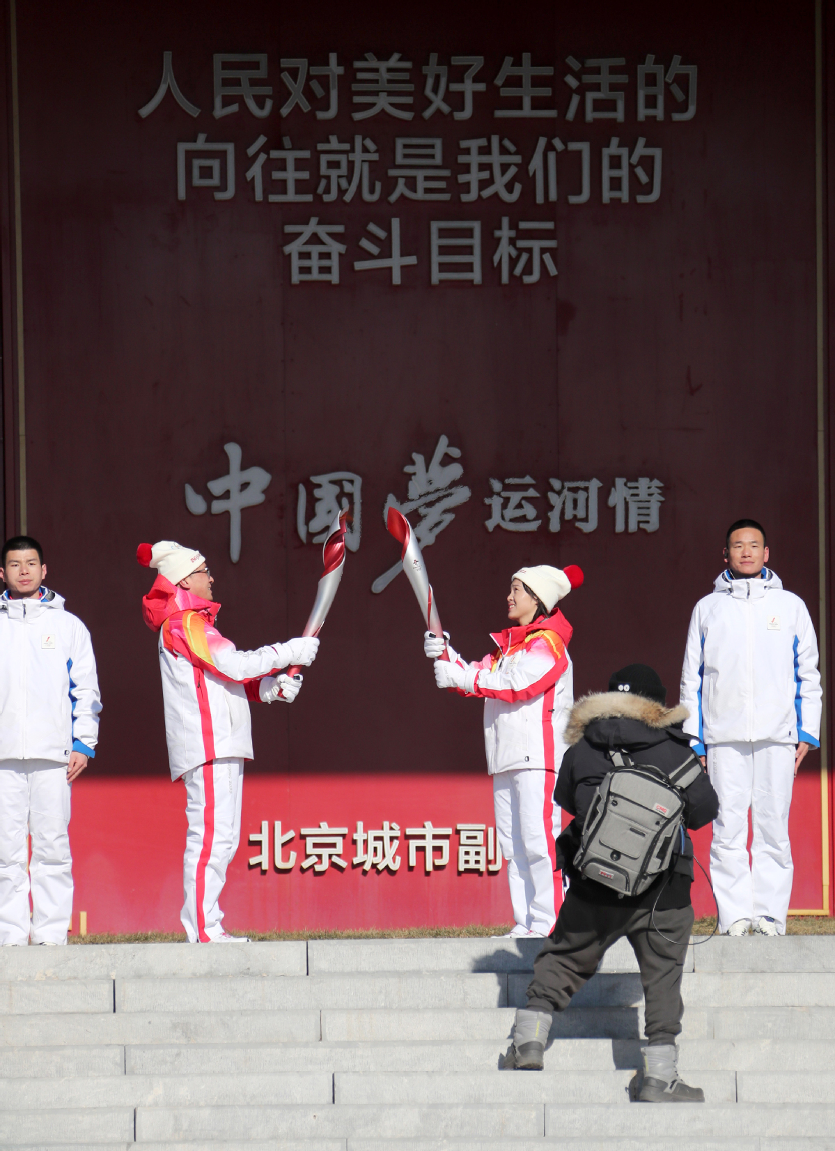2月4日，火炬手谢宝松（左）与佘萌进行火炬传递。中国日报记者 王敬 摄