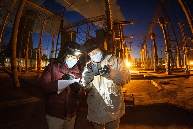 内蒙古大唐国际托克托发电有限责任公司发电部运行值班员张天奇（左一）和同事冒着严寒在查看涉网设备。（朱森 摄）