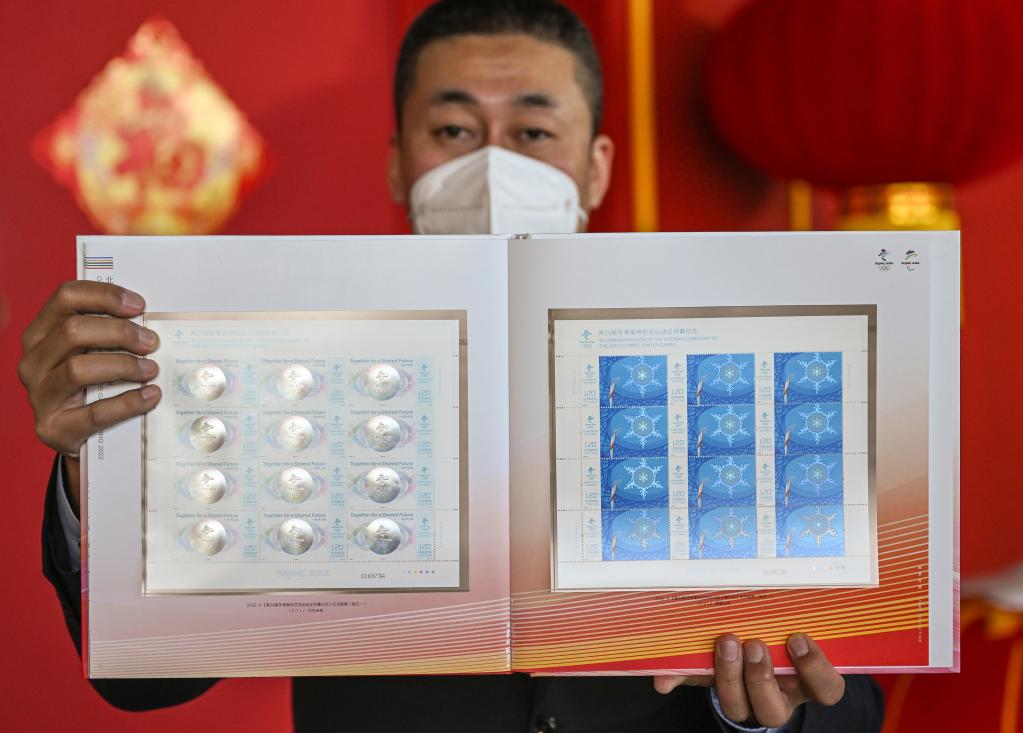 2月5日，一名工作人员在北京冬奥会主媒体中心展示纪念邮票。新华社记者李贺摄