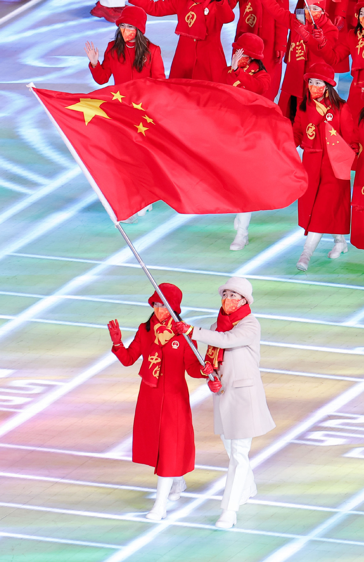 中国代表团旗手赵丹（下左）、高亭宇（下右）在开幕式上入场。（图片来源：新华社）