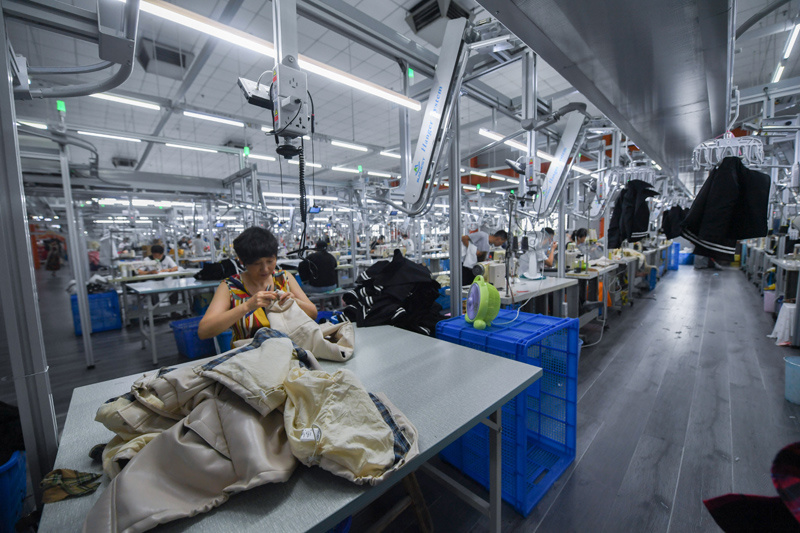 工作人员在位于浙江省湖州市织里镇的湖州朗田服饰有限公司流水线上