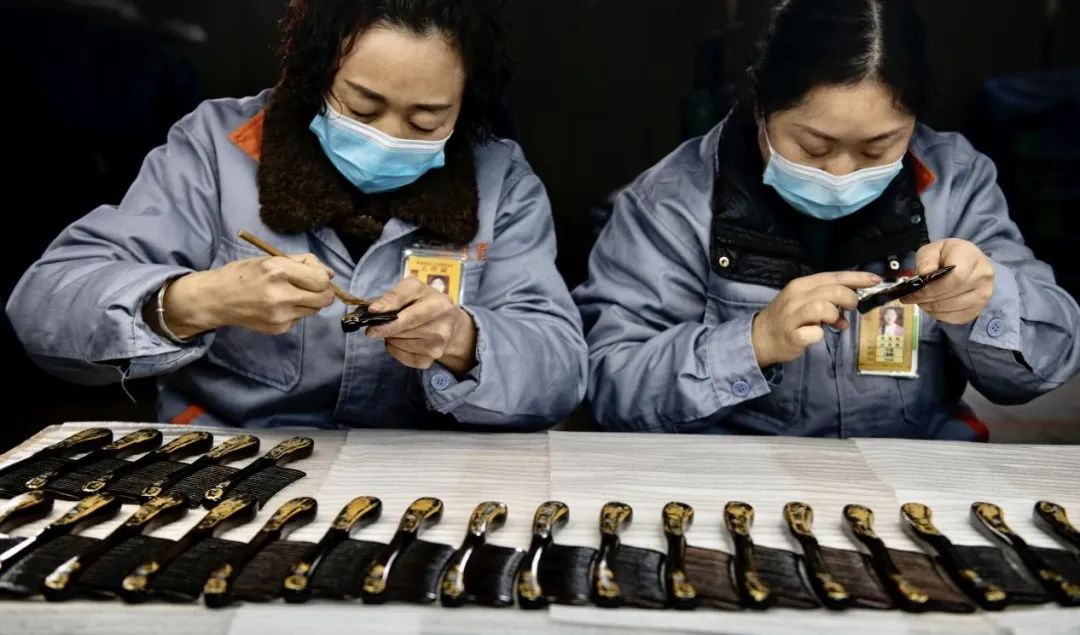 谭木匠重庆万州工厂，工人们熟练地贴金箔。 冉孟军 摄