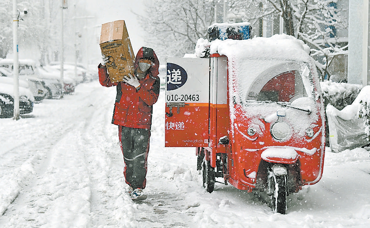 大雪纷飞,在北京通州一小区,快递员冒雪为居民送着快递.
