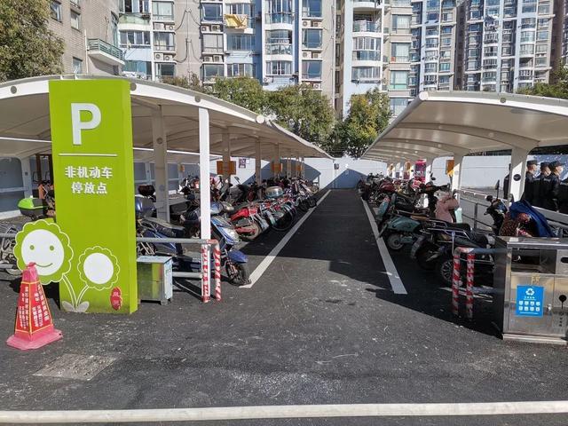 改造后的非机动车智能停车棚"以前我们都是停到店铺门口,用接线板充电