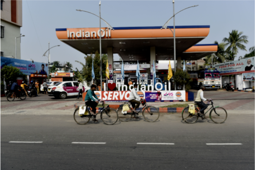 印度街头，几个年轻人骑车驶过一处加油站。图/ICphoto