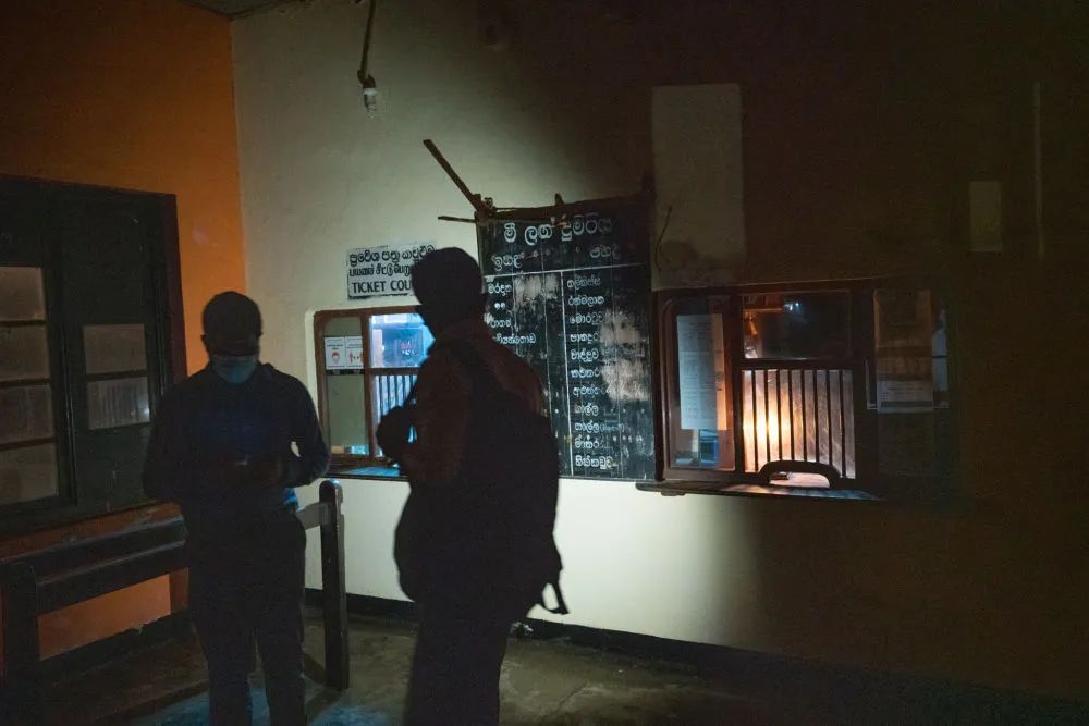 3月31日，在斯里兰卡科伦坡一处火车站，人们在售票处停电后借着微弱灯光查看火车信息。图片来源：新华社