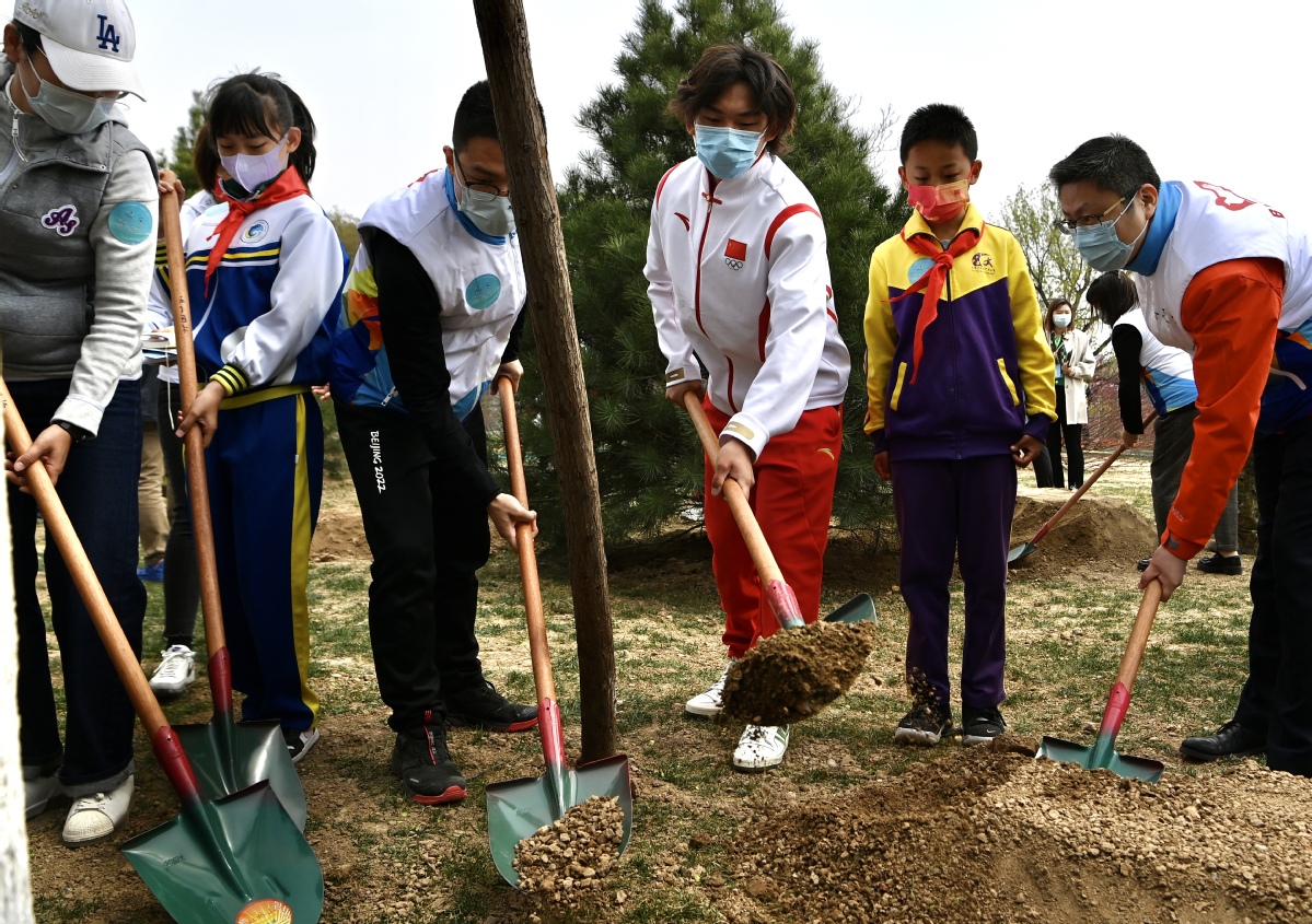 北京冬奥公园内的“中国冰雪冠军林”， 苏翊鸣（中）与参加活动的青少年等共同植树添新绿。（中国日报记者 魏晓昊 摄）