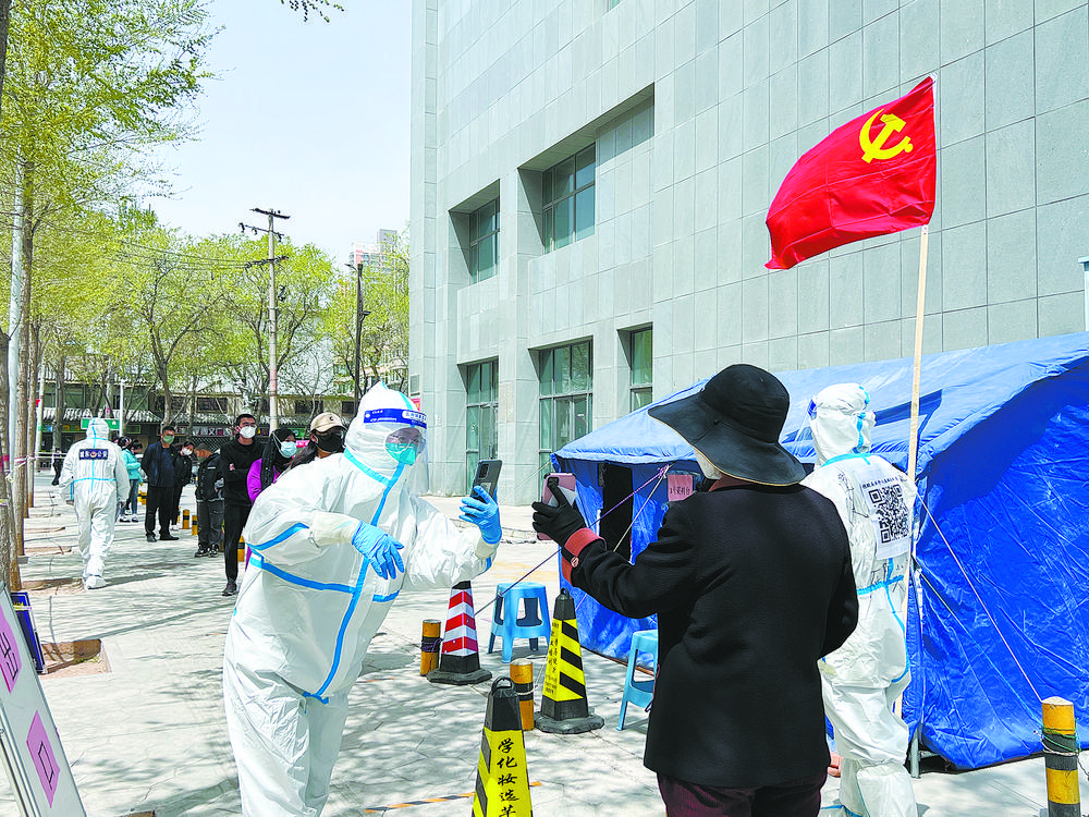 下滨河路巷道口核酸检测点上，市民们在工作人员的帮助下进行扫码信息录入工作。城东组 供图