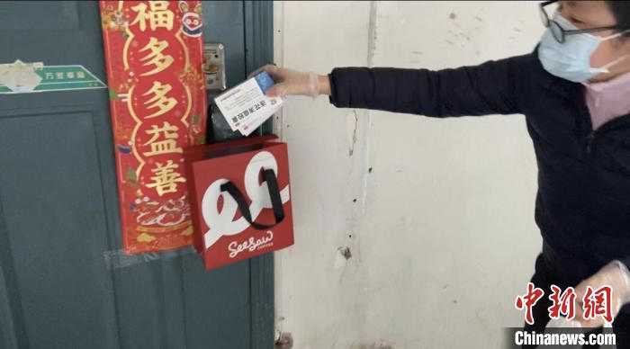 志愿者向居民发放连花清瘟胶囊。图片来源：中新网