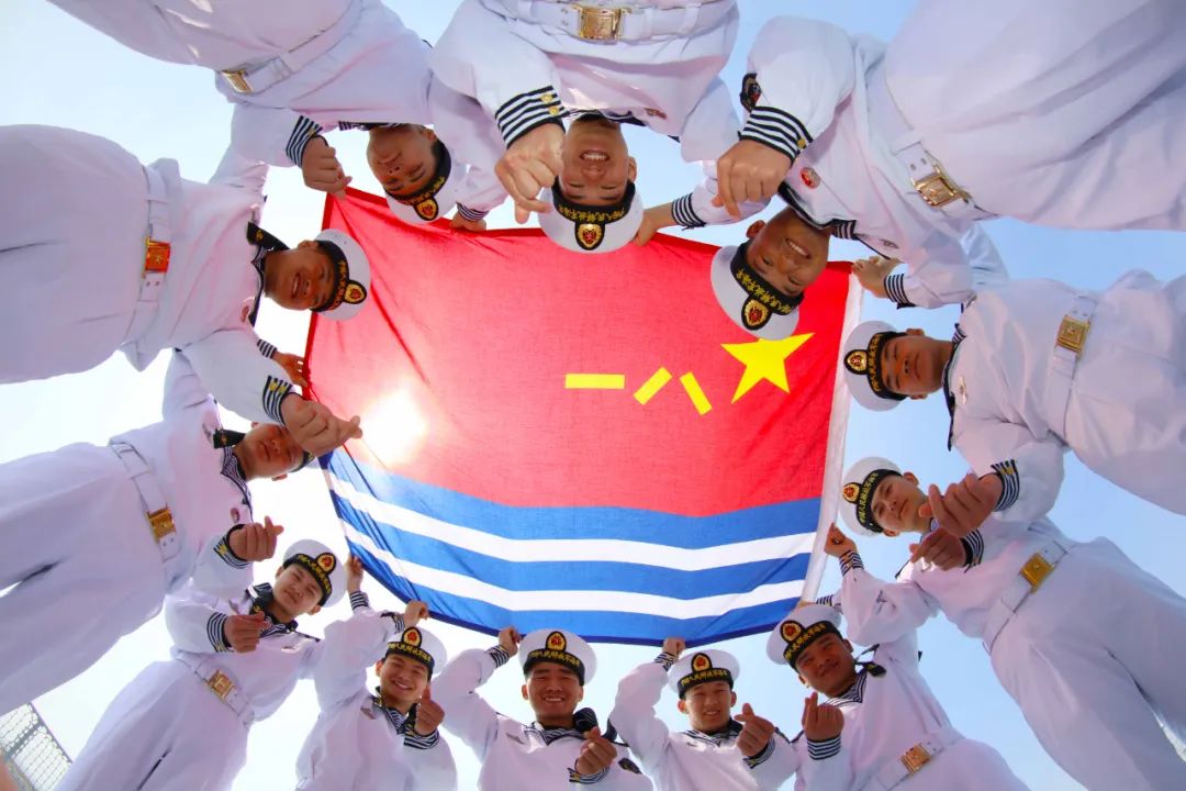▲某护卫舰支队官兵簇拥着鲜艳的海军旗送上节日祝福。