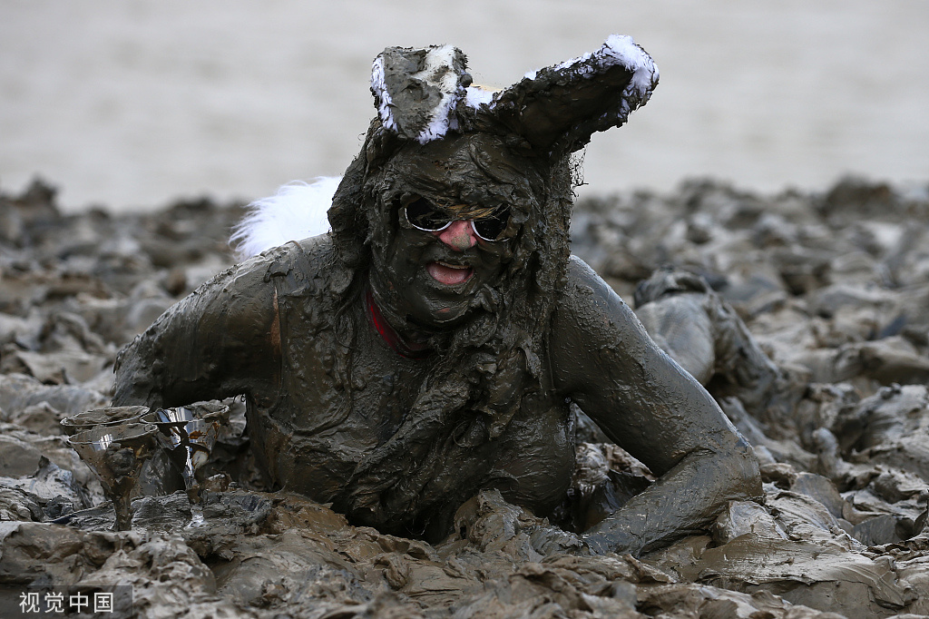 英国举行滚泥巴大赛民众在泥堆里匍匐前进
