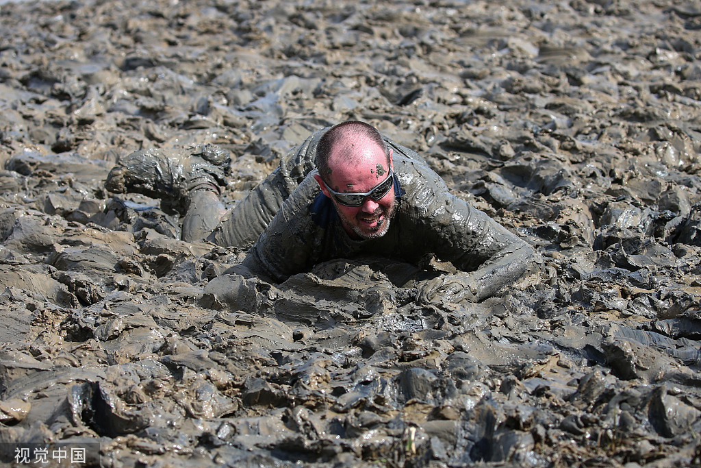 英国举行滚泥巴大赛民众在泥堆里匍匐前进