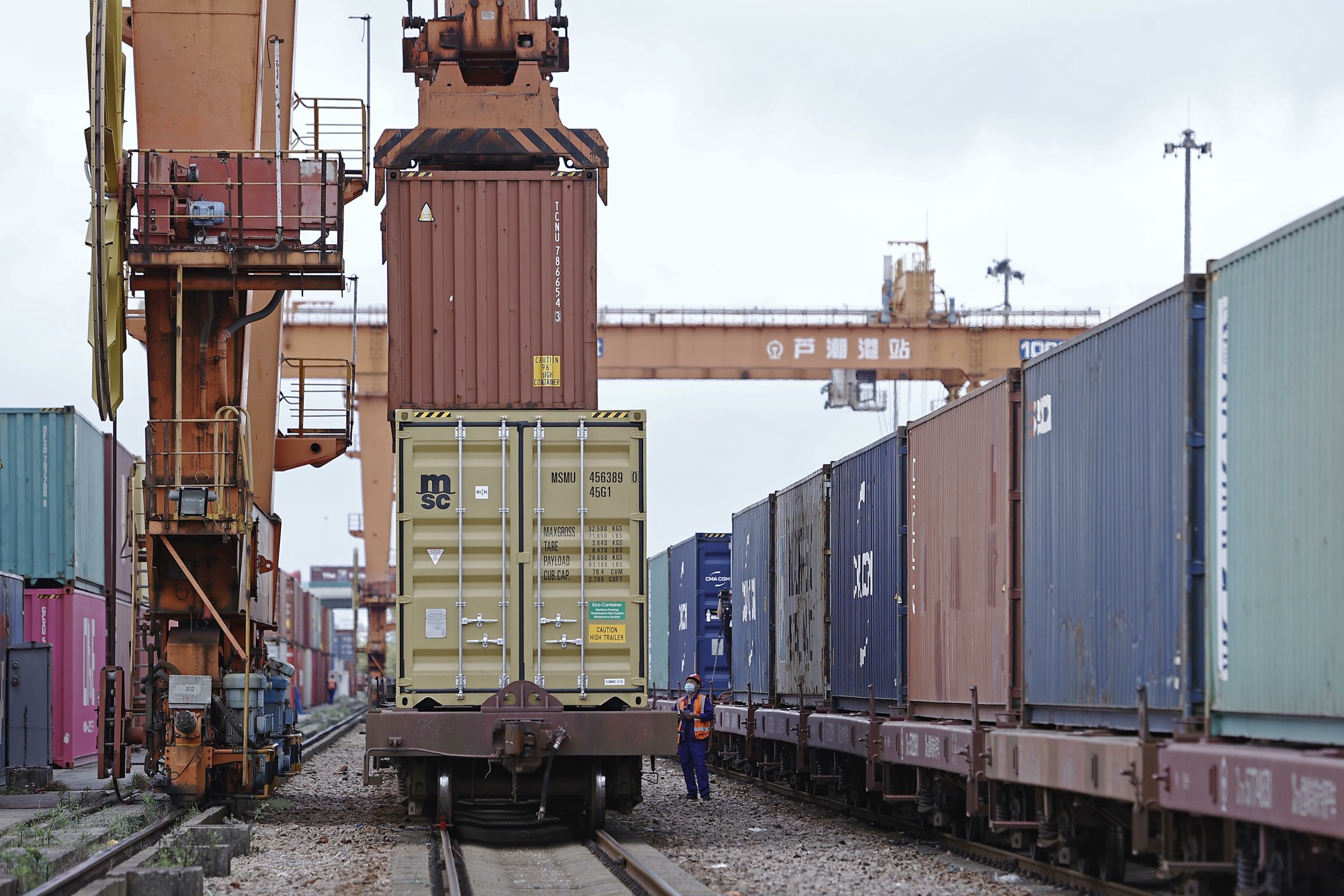 64,-5.10%))4月24日,上海芦潮港中心站工作人员正在引导集装箱装车.