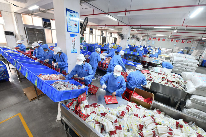 在广西中柳食品科技有限公司生产车间,工人在生产线上包装螺蛳粉(4月