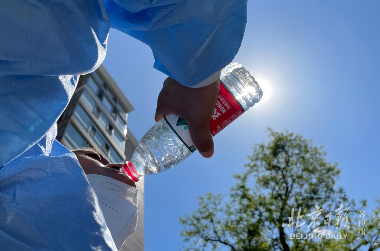 忙完四号楼物资运送、垃圾清运，大汗淋漓的运输组成员一口气喝完一瓶水。