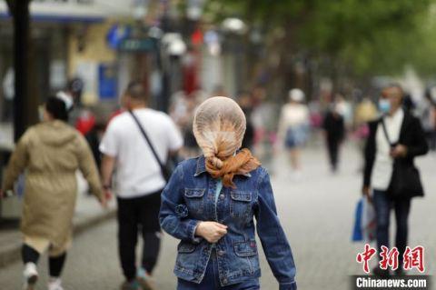 行人在风中用纱巾裹头前行. 姜辉 摄