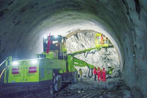 图为火山隧道内,施工人员正操作全电脑控制的三臂台车进行开挖作业.