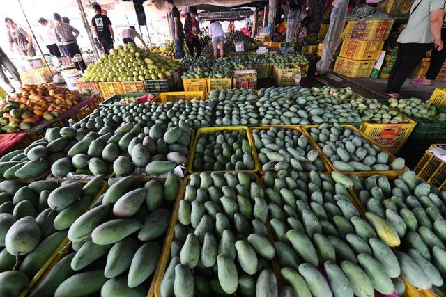 农副产品综合批发市场,人们在交易刚收获的芒果(2021年7月1日摄)