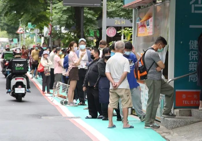 图为岛内某药局前,台湾民众大排长龙,等待购买快筛试剂的场景.