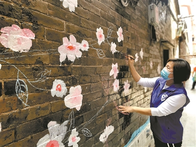 志愿者在美化旧房墙面.一面墙变成了一幅画.