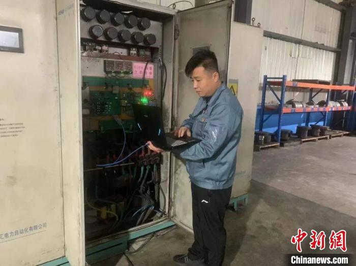 周胜勇带着笔记本电脑，穿梭于大型机器间为设备“把脉”。上海市工商联 摄