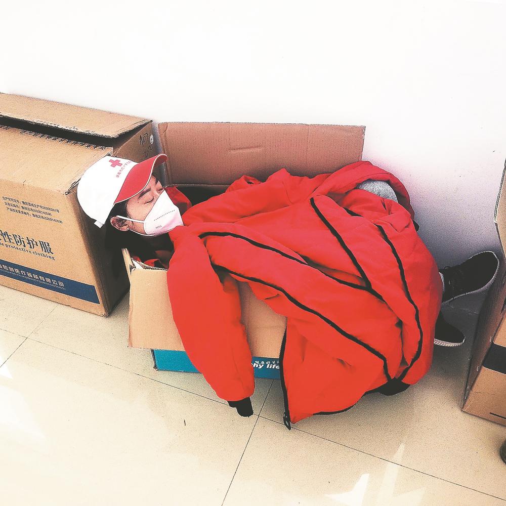 日前,在淮南奥体中心核酸检测基地,志愿者黄春艳蜷曲在纸箱里睡着了.