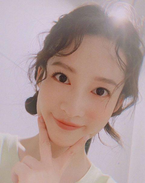 李沁晒双丸子头卷发自拍手拿鲜花对镜微笑