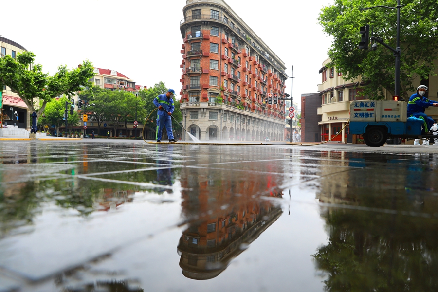 5月19日，在上海武康大楼前，清洁工人使用水枪清洗路面。 中国日报记者 朱兴鑫 摄