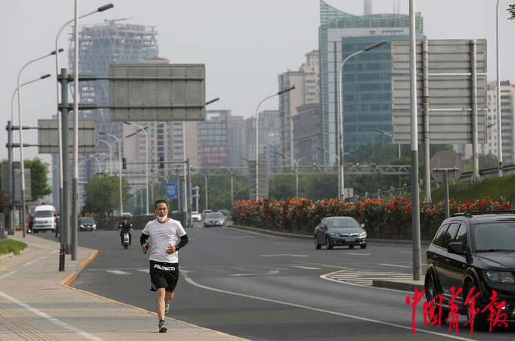 5月19日，北京市东四环辅路边的人行道，一名年轻人正在跑步锻炼身体。中青报·中青网记者 陈剑/ 摄