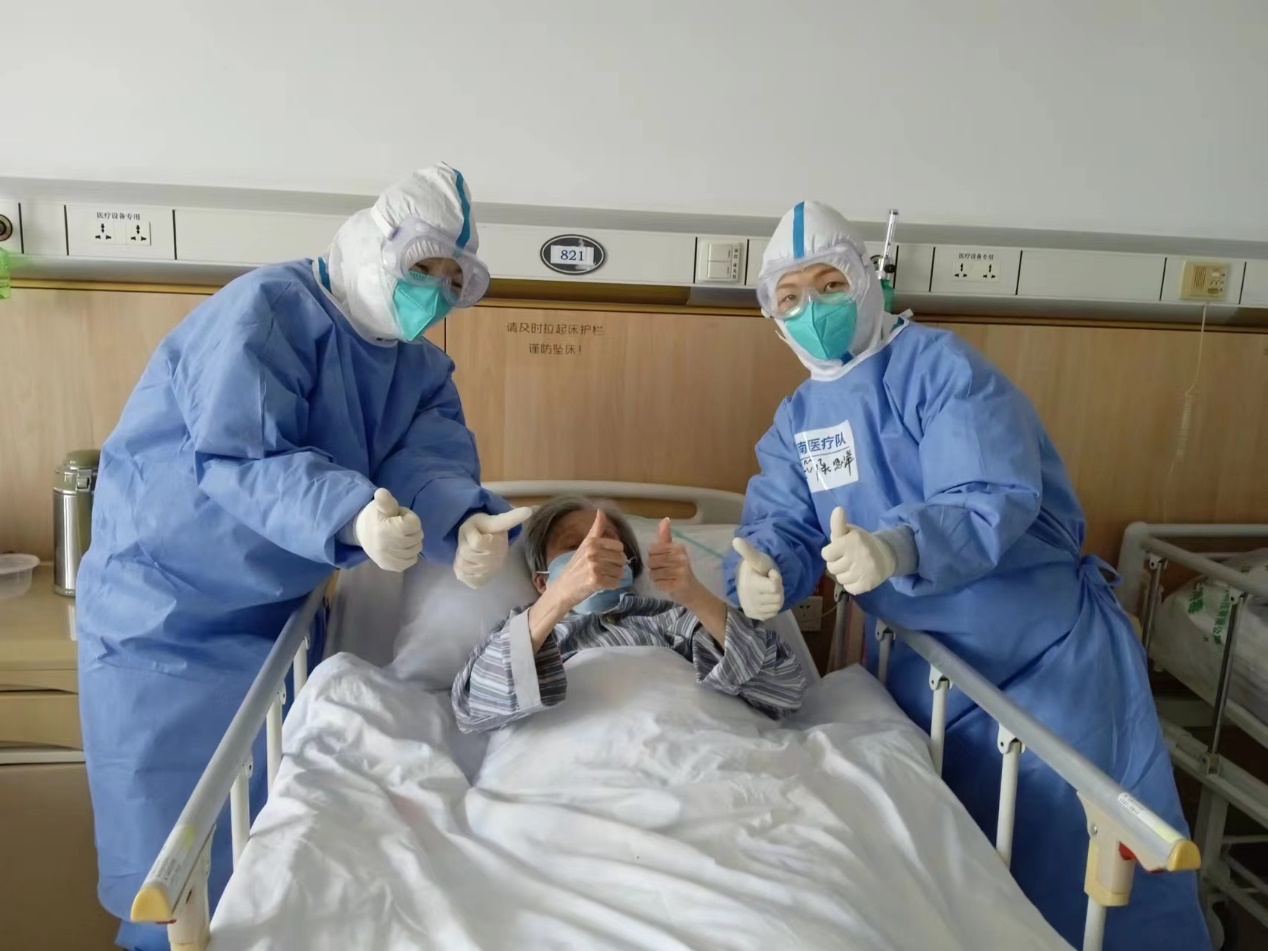 嘉定区安亭医院，海南医疗队两名队员给患者做完俯卧位治疗后，老人高兴地竖起联勤大拇指