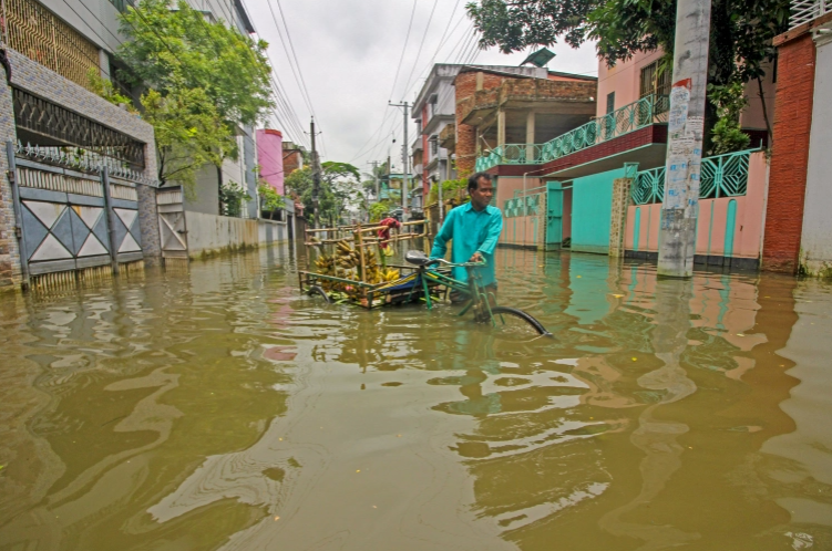 △5月21日，一名商贩在孟加拉国锡尔赫特被洪水淹没的道路上贩卖香蕉