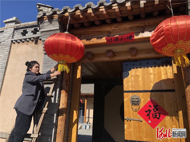 刘娇把大红灯笼挂在民宿小院门前,准备开门迎客.