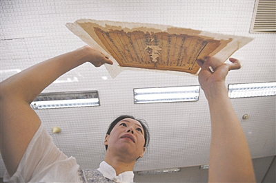 图为修复师正在展示“重获新生”的古籍（资料图片）。 崔健 摄