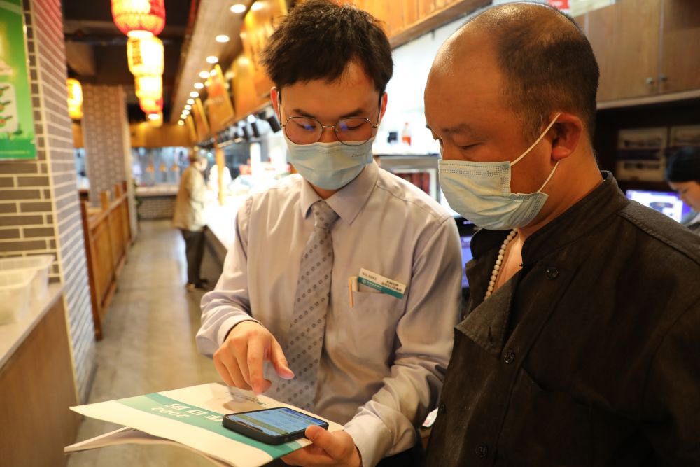 农行金华分行客户经理指导餐饮店主办理无还本续贷业务.(受访者供图)