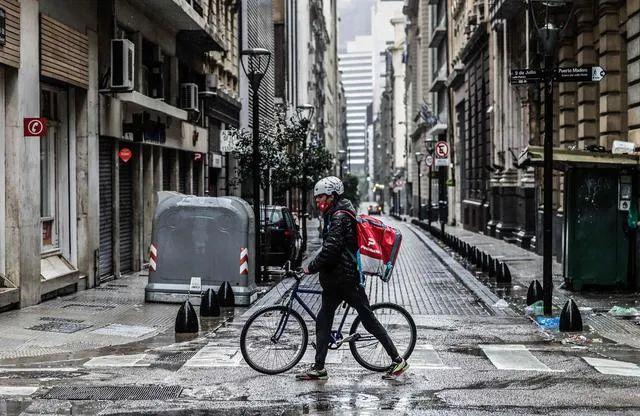 ▲2021年5月22日，阿根廷布宜诺斯艾利斯一名送餐员走过空旷的街道。图/新华社