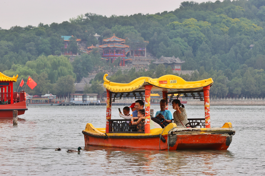 6月3日，游客乘船近距离观看颐和园昆明湖上的野鸭。中国日报记者 姜东 摄