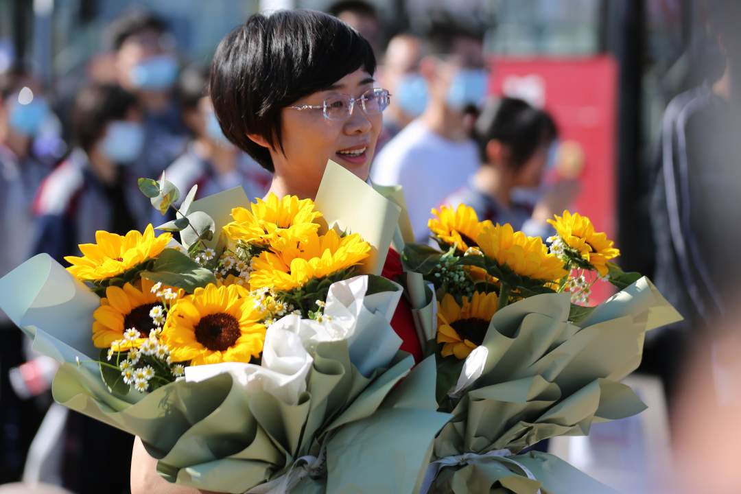 6月7日,家长手持鲜花在山东省沂南县沂南一中考点外等候考生.