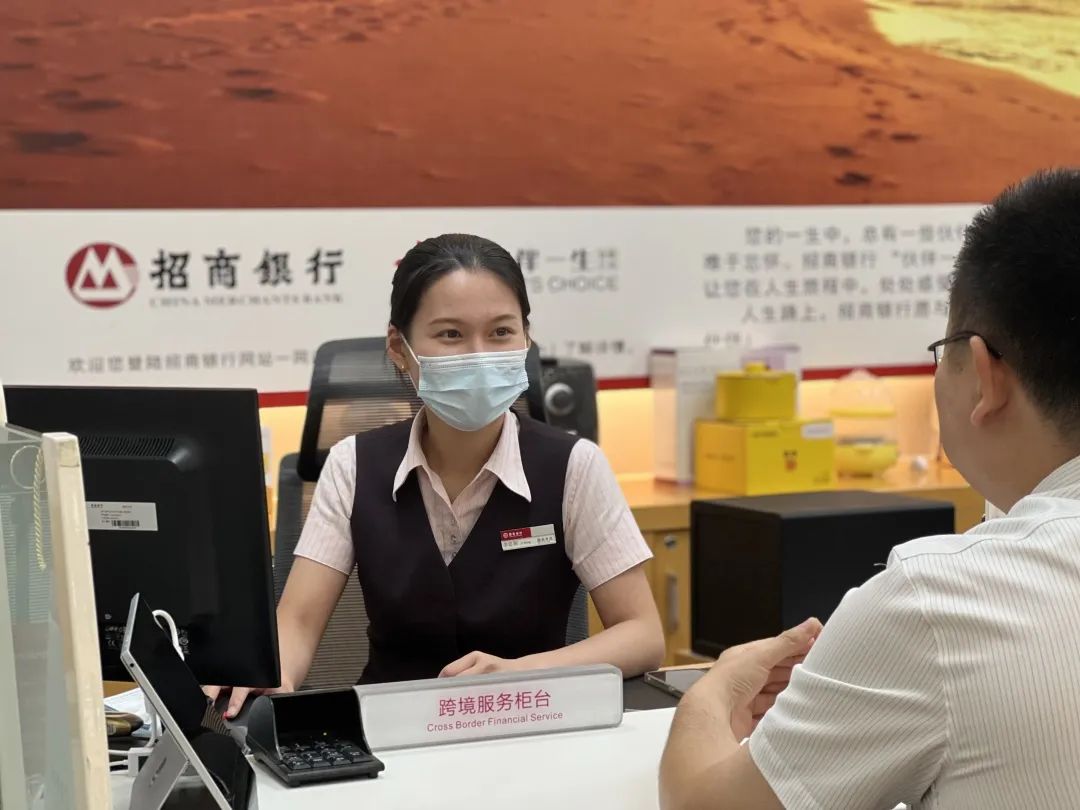 招商银行海口分行营业部跨境服务专属柜台内,柜员办理自贸业务