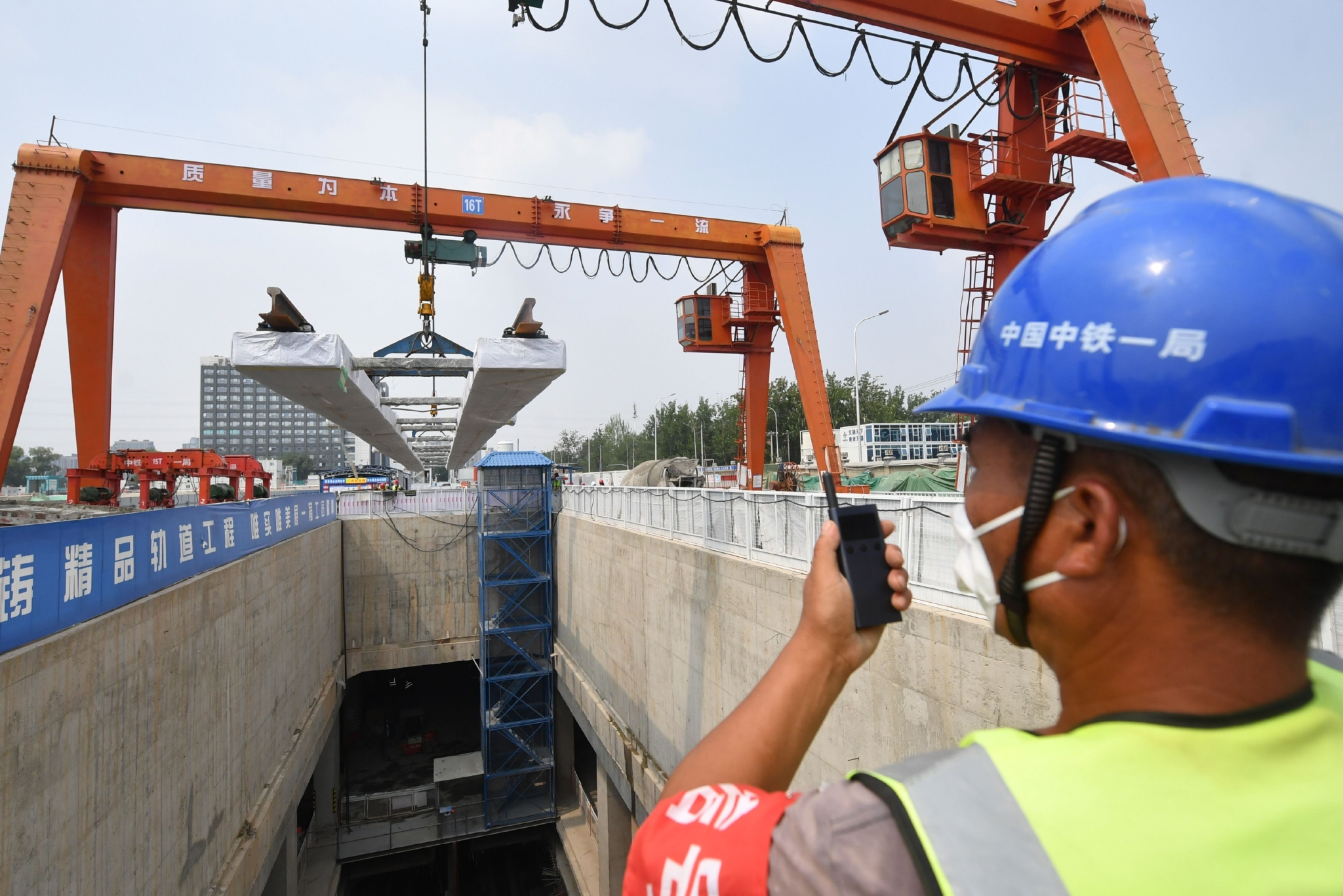 地铁昌平线南延建设现场,工作人员正在指挥吊装轨排.