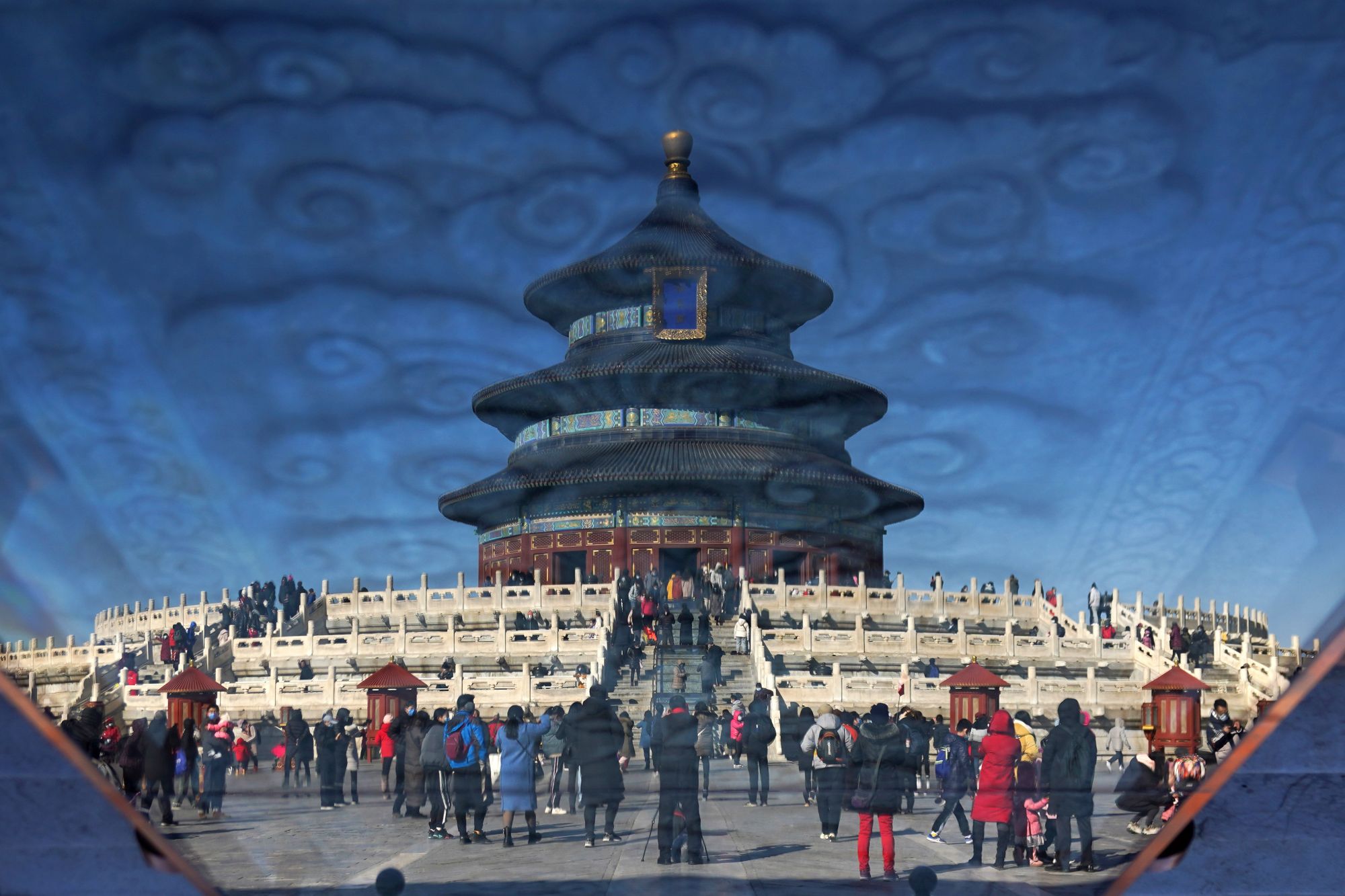 这是2021年2月17日通过玻璃反光拍摄的游客在天坛公园参观游览(照片