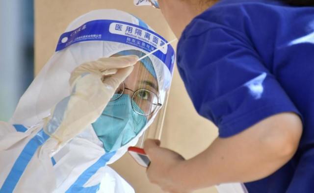 护士在北京朝阳区八里庄街道一处核酸检测现场为居民进行核酸检测采样