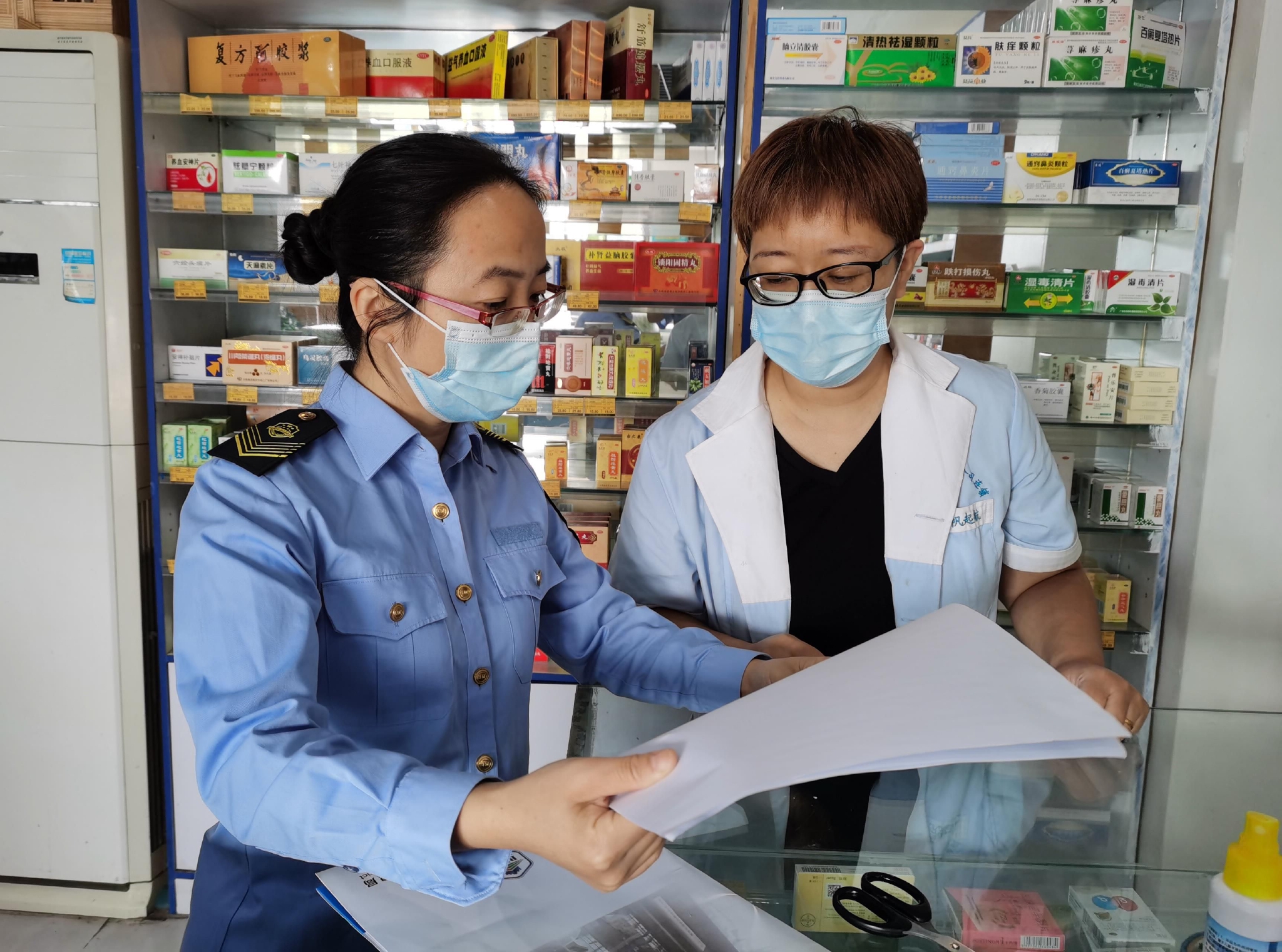 执法人员查看药店员工体温记录和场所消毒记录.&nbsp; 邵敏/摄